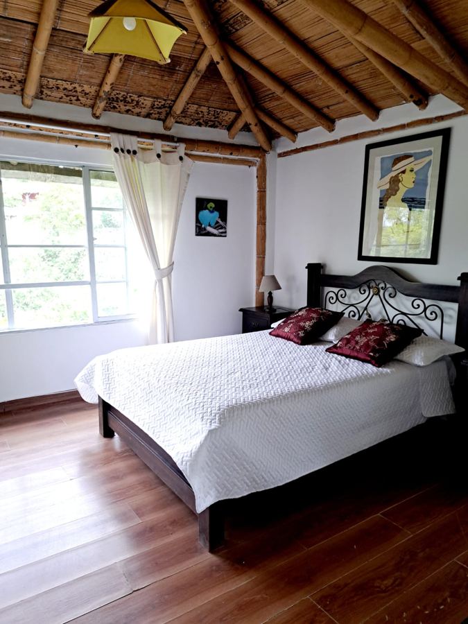 Habitación principal con cama doble, piso en madera y ventanal